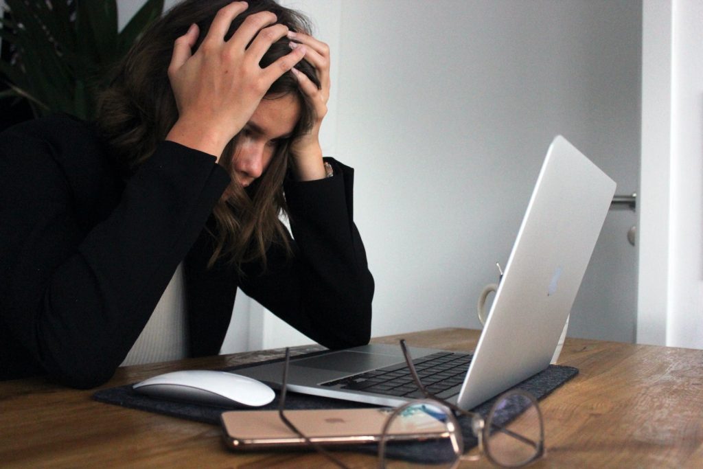 woman in black long sleeve shirt covering her face with her hands